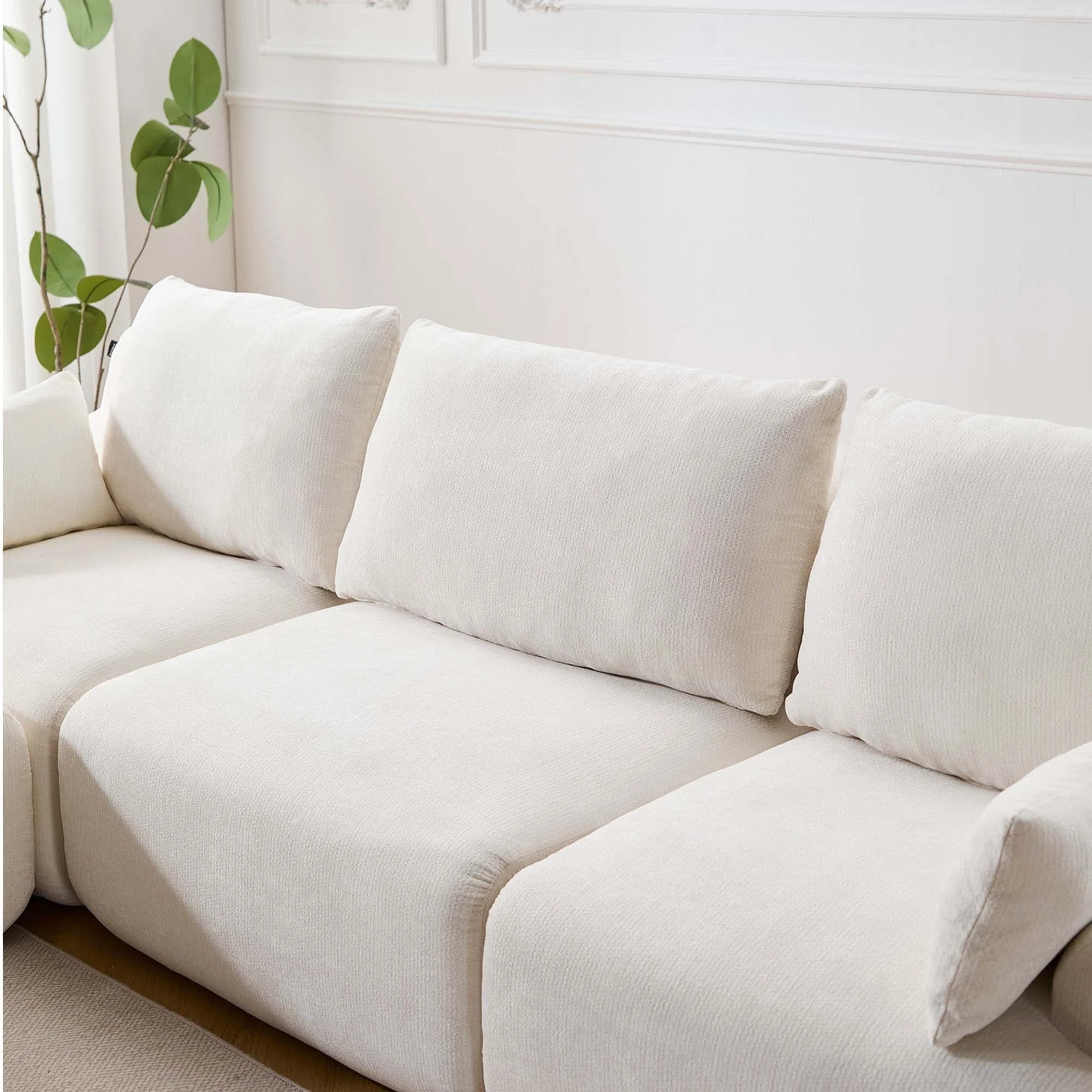 Canapé d’angle beige clair avec coussins décoratifs et assise profonde