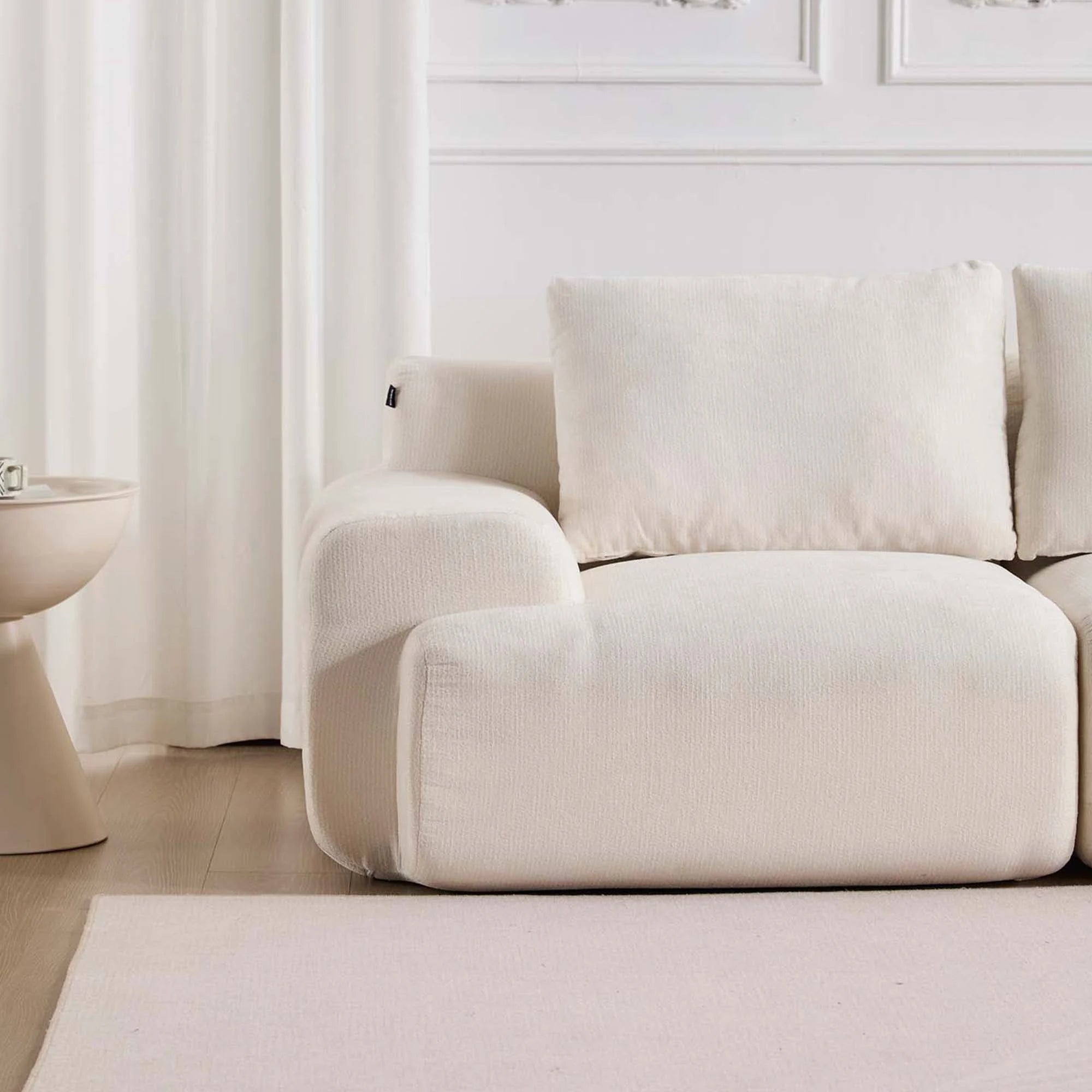 Canapé d’angle en tissu beige clair avec pouf et coussins carrés